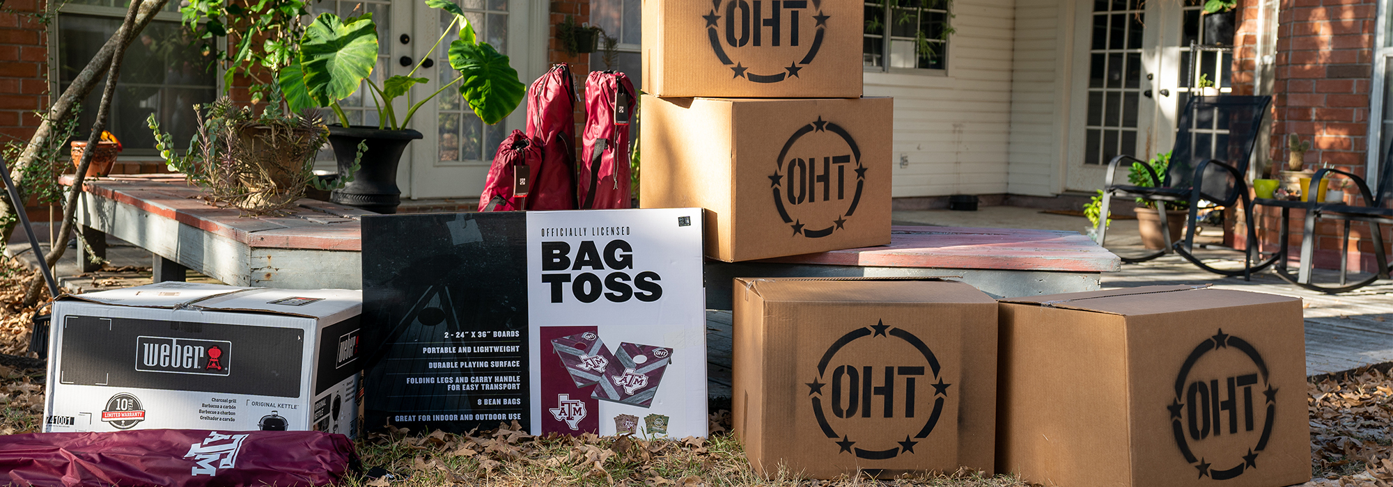 OHT branded boxes stacked in a backyard where the TAMU team was going to surprise the student veteran.