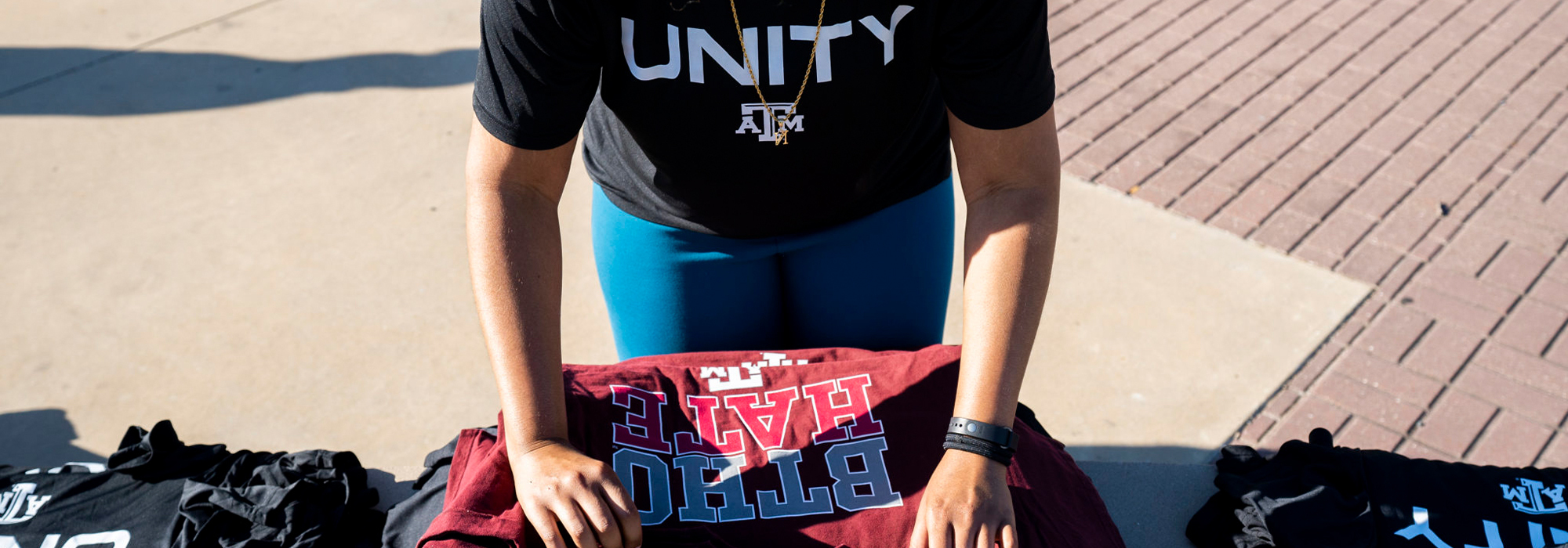 Women wearing TAMU Unity shirt folding BTHO hate shirts