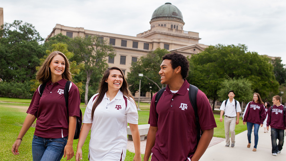 Texas A&M students walking outside the academic building wearing branded polos