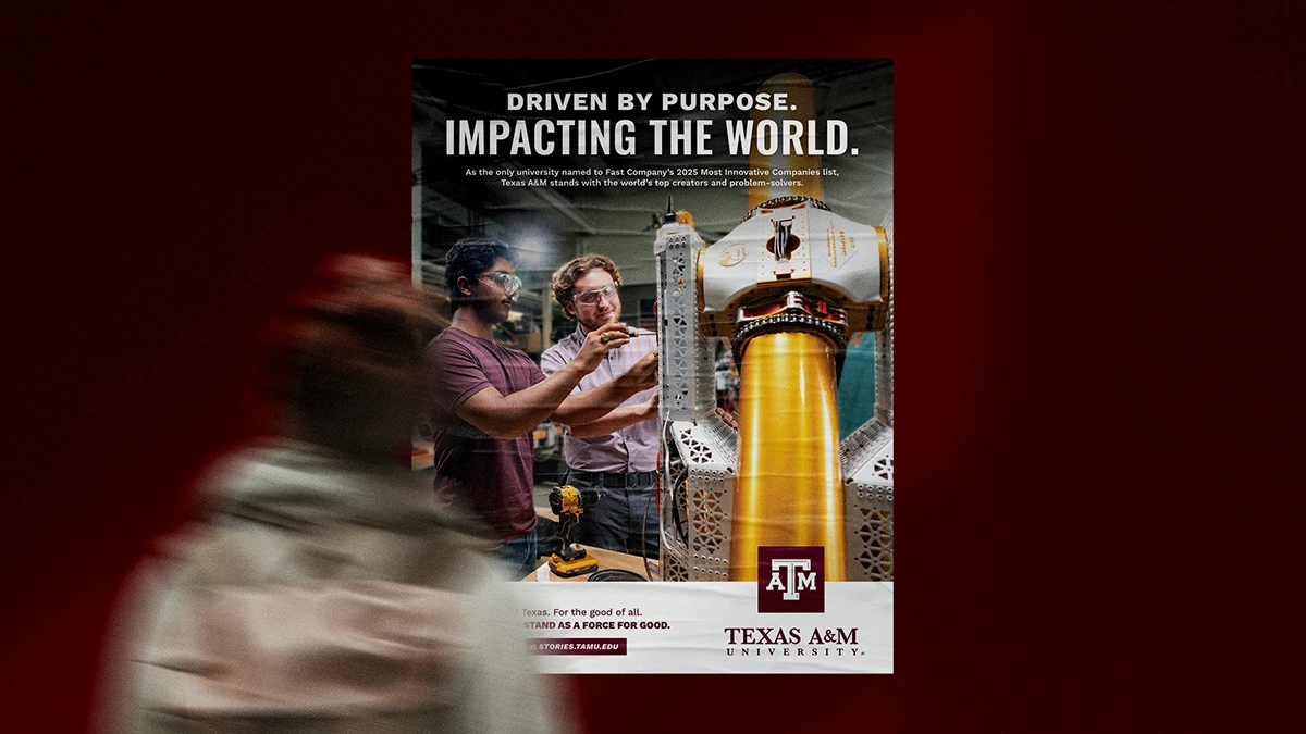 A Texas A&M ad on a poster featuring two students wearing safety goggles using tools to interact with a robot under the headline "Driven by purpose. Impacting the world."