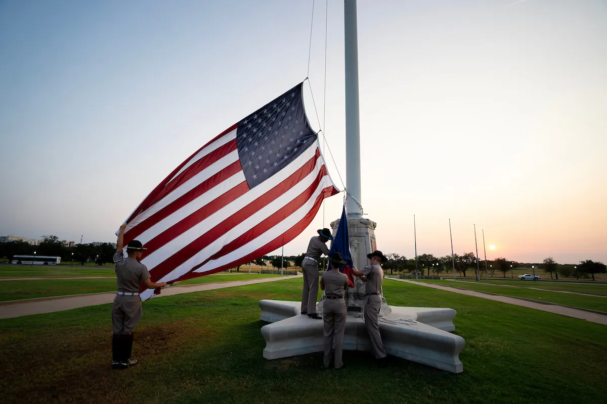 Epic photo of cadets rising the American flag on the main campus flagpole at sunrise