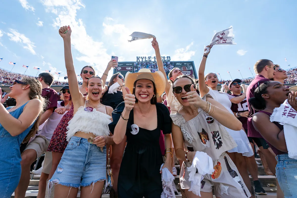 Group photo at an Aggie football game of fans celebrating and posing for the camera